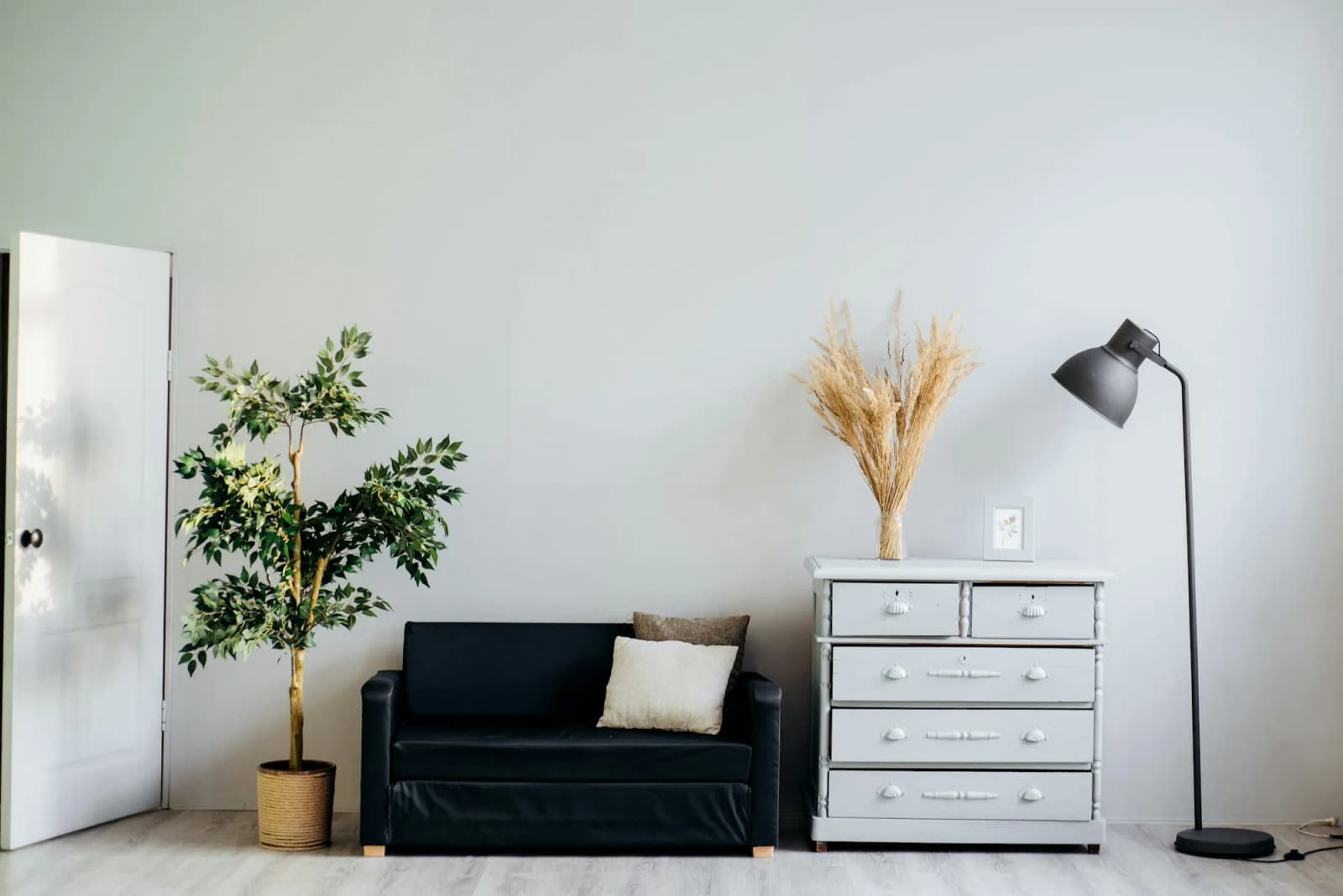 Cómoda, candeeiro de pé e plantas num quarto